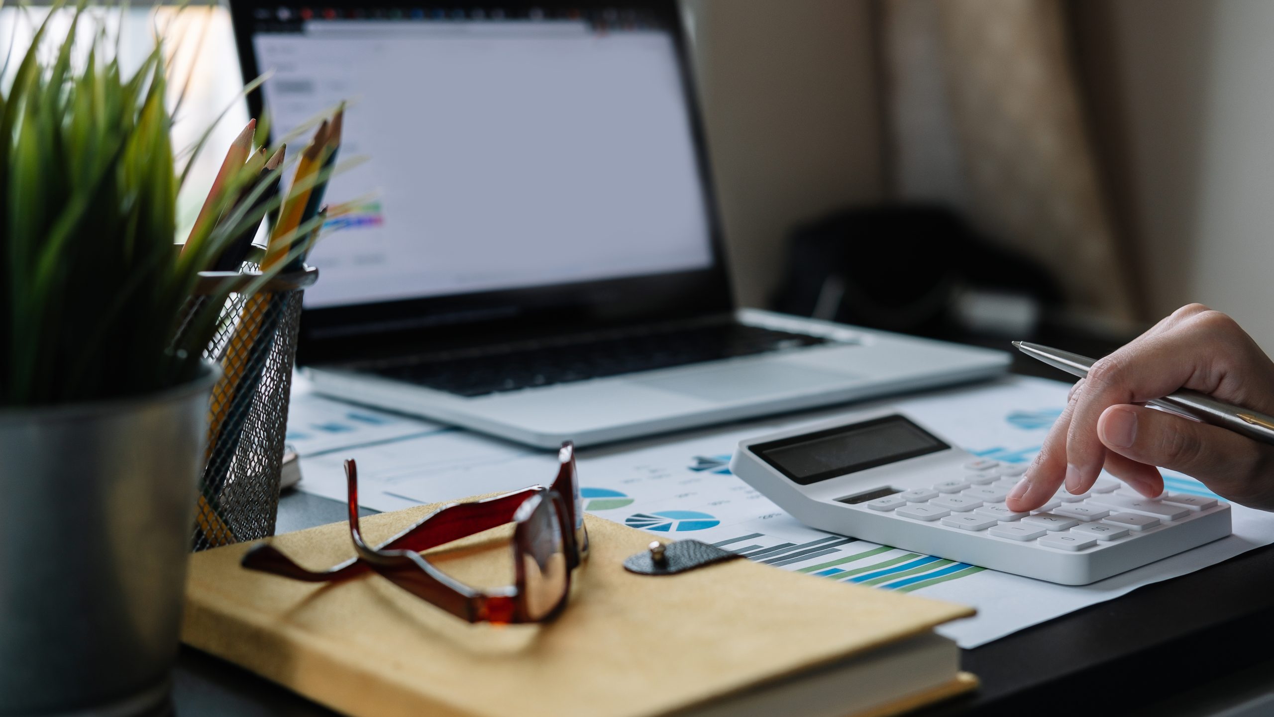 accountant working on desk using calculator for calculate finance report at home.