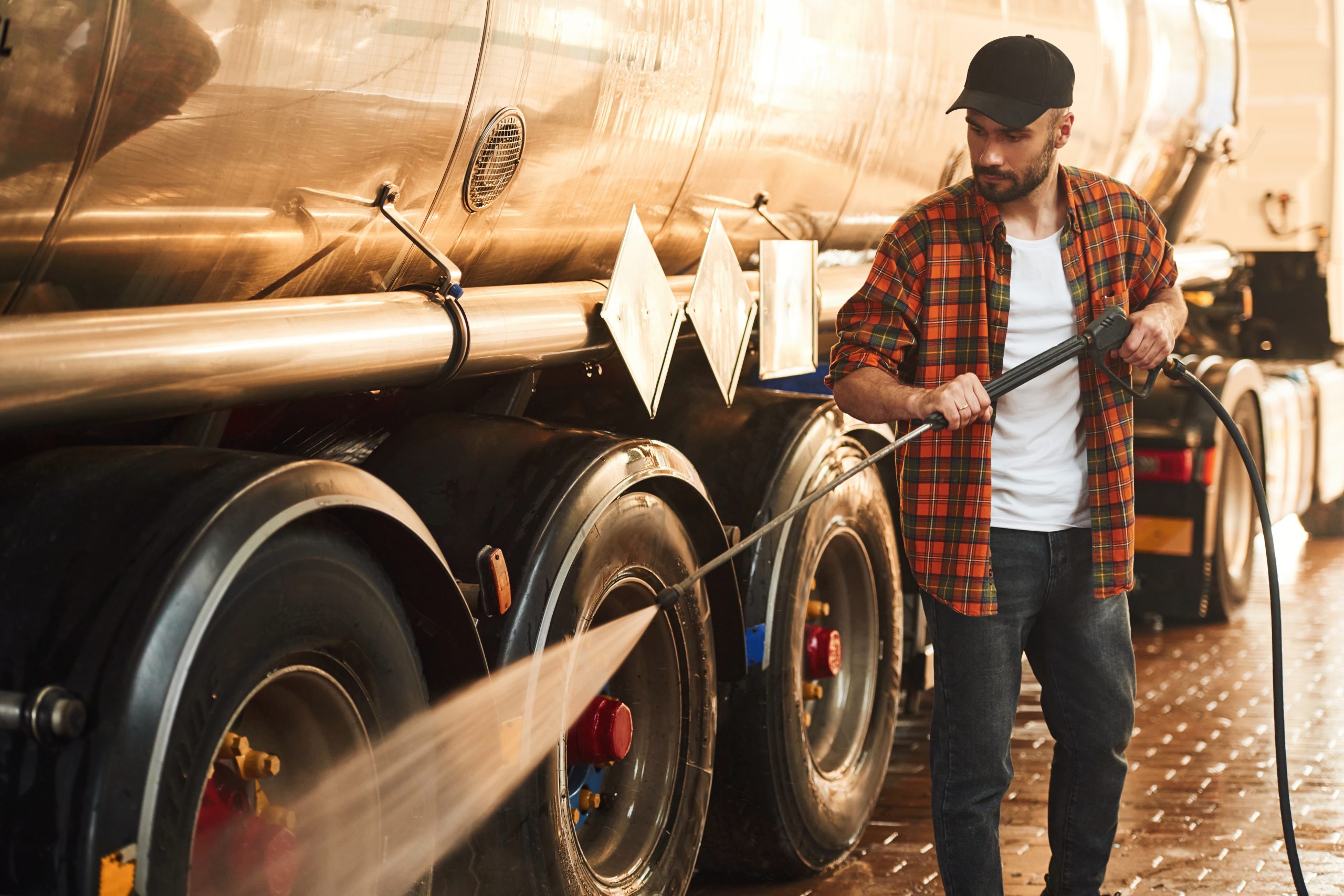 Idropulitrice Washing the vehicle. Young truck driver in casual clothes Idropulitrice Washing the vehicle. Young truck driver in casual clothes.